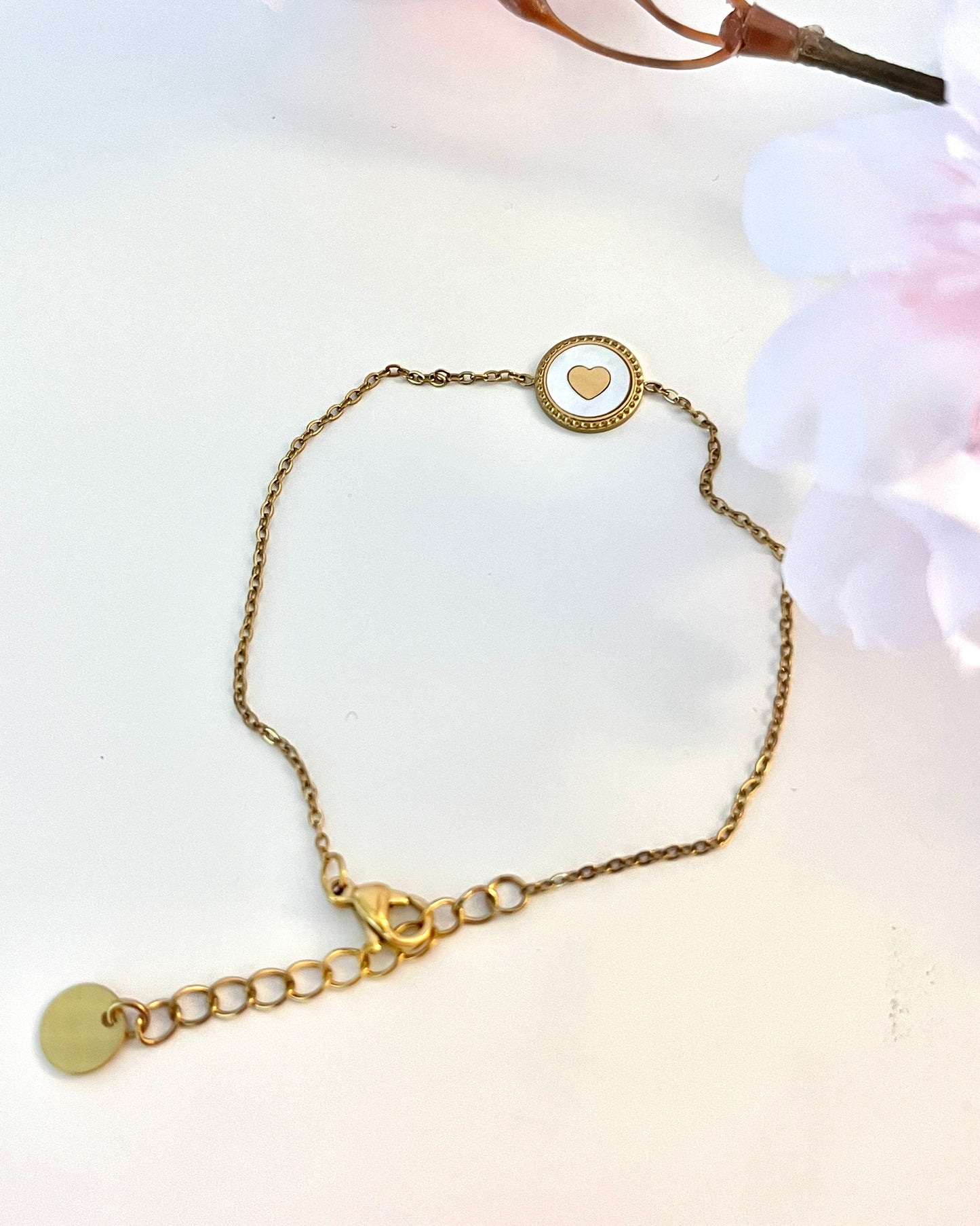 On fond devant ce joli bracelet fin dégageant une chaleur de tendresse, réalisé en acier inoxydable plaqué or, avec incrustation d'un coeur façon médaille