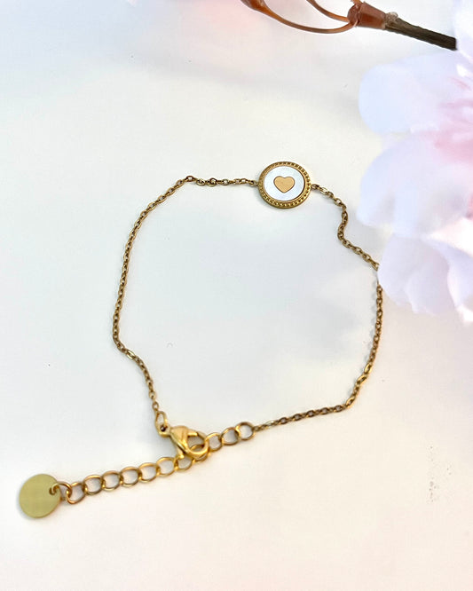 On fond devant ce joli bracelet fin dégageant une chaleur de tendresse, réalisé en acier inoxydable plaqué or, avec incrustation d'un coeur façon médaille