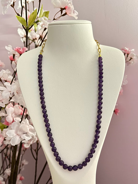 Collier long, type sautoir, chaine de maillons originaux et dorés dans la nuque, et belle longueur de perles rondes d'améthyste, pierre naturelle qui aiderait à apaiser l'esprit, favoriser l'intuition, retrouver calme, clarté, sérénité intérieure.